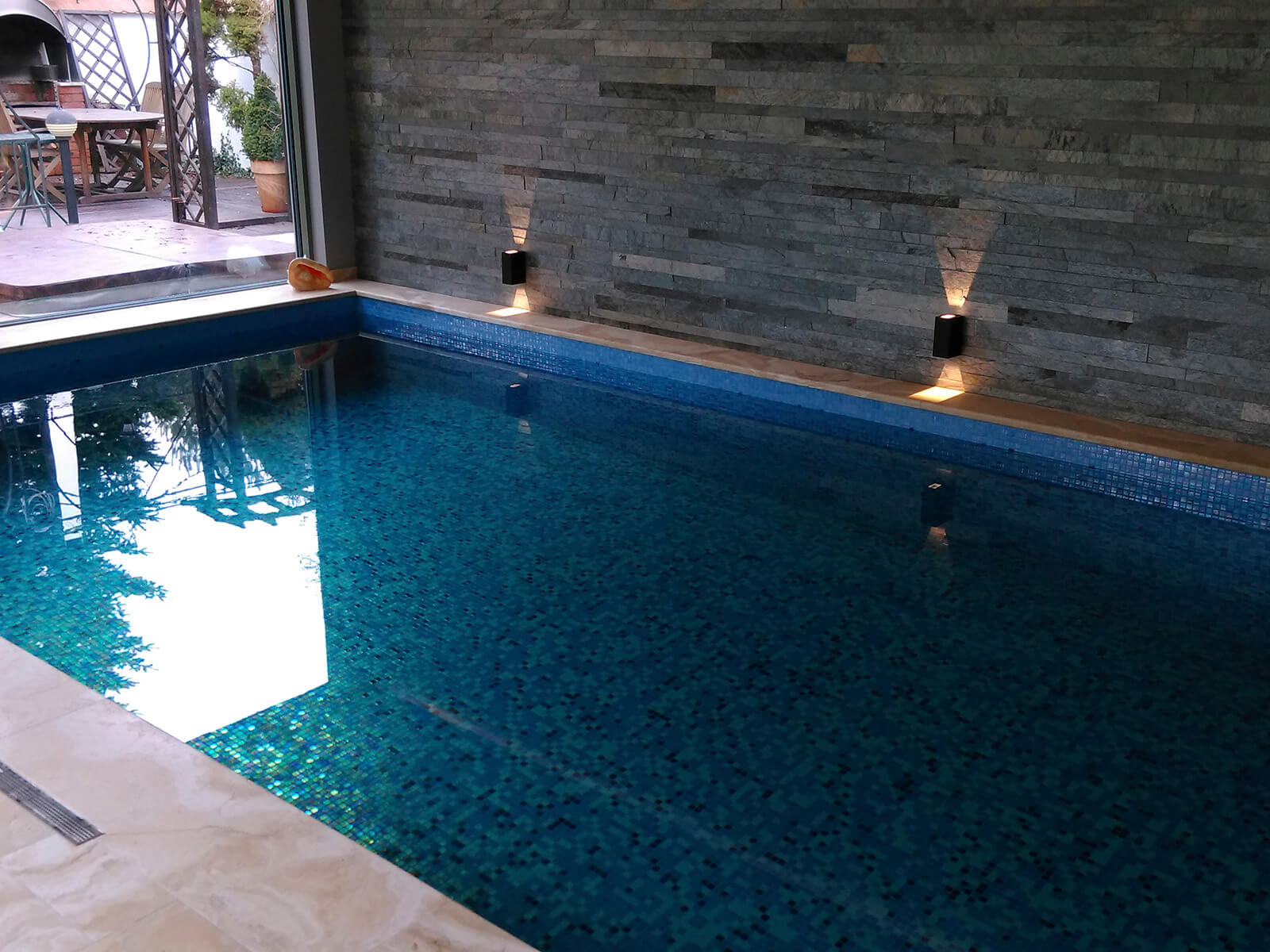 Prachtig verlicht binnenzwembad in koude blauwtinten mix glasmozaïek zwembad tegels
